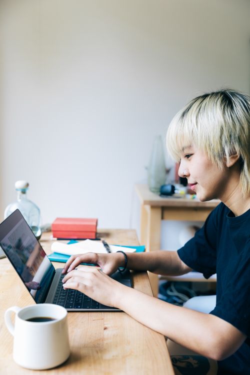 Close-up of a person typing on a laptop at a table